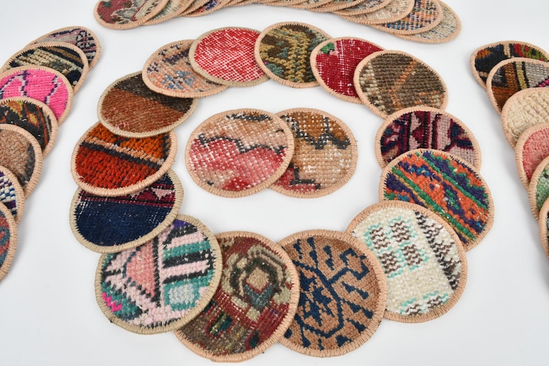 May include: A set of round, colorful coasters made from woven fabric with a beige border. The coasters are arranged in a circle pattern.