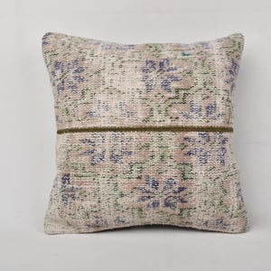 May include: A square cushion with a cream background and a floral pattern in shades of blue, green, and pink. The cushion has a brown trim around the edges.