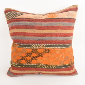 May include: A decorative pillow with a woven design. The pillow features horizontal stripes in shades of red, orange, and gray. The lower section has an orange background with a geometric pattern. The pillow is square-shaped.