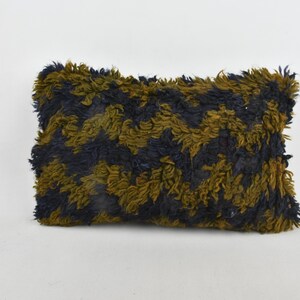 Könnte beinhalten: Ein rechteckiges Kissen mit einer flauschigen Textur. Das Kissen ist aus dunkelblauem und olivgrünem Stoff mit einem marmorierten Muster.