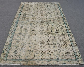 May include: A vintage rug with a cream background and a repeating floral pattern in shades of blue and black. The rug has a fringed edge.