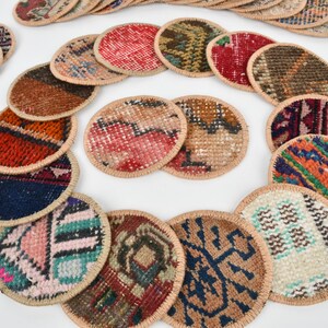 May include: A set of round, colorful coasters made from woven fabric with a beige border. The coasters feature various patterns and designs.