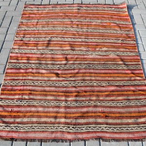 May include: A vintage striped rug with a brown, orange, and white color scheme. The rug has a woven texture and a fringe border.
