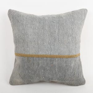Op de afbeelding: Een vierkant, grijs decoratief kussen met een textuur. Een dunne, horizontale gouden band accentueert het midden van het kussen. Het kussen is gemaakt van een geweven stof en is geschikt voor woondecoratie.