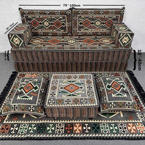 Puede incluir: Un juego de sala de estar completo con un sofá (190 cm de ancho), dos reposabrazos, una mesa de centro, dos cojines de suelo y una alfombra. El conjunto tiene un patrón geométrico gris, marrón y naranja. El sofá tiene 70 cm de profundidad y 40 cm de altura.