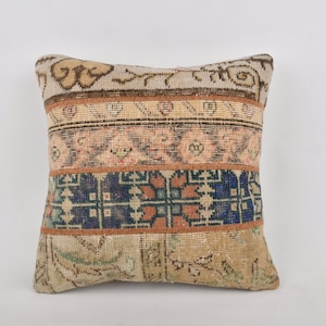 May include: A square throw pillow with a patchwork design. The pillow is made from a variety of vintage fabrics with different patterns and colors, including beige, brown, blue, and pink.