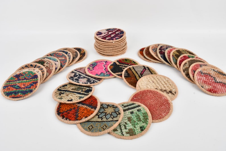 May include: A set of round, colorful coasters made from woven fabric with a beige border. The coasters are arranged in a circle with a stack of coasters in the background.