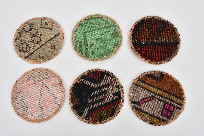 May include: Six round coasters made from colorful patterned fabric with a beige border. The coasters are approximately 3 inches in diameter.