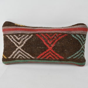 May include: A brown rectangular pillow with a geometric pattern in shades of red, white, green, and yellow.