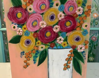 May include: A rectangular painting on a light pink background featuring a bouquet of colorful flowers in a white vase. The flowers are painted in shades of magenta, yellow, pink, and orange with green leaves. The artwork is displayed on a black stand.