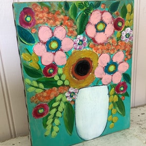 May include: A rectangular painting on a wooden panel featuring a vibrant floral arrangement in a white vase against a bright turquoise background. The artwork displays pink, yellow, and red flowers with green leaves and orange textured accents.