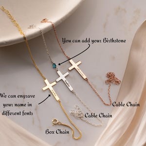 May include: Three personalised cross bracelets in gold, silver, and rose gold. Each bracelet features a cross pendant and a name engraved on a bar. The image also shows the text "You can add your Birthstone" and "We can engrave your name in different fonts."