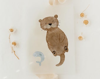 May include: A watercolor illustration of a brown otter with a small blue fish swimming below it. The otter is smiling and has a light brown body with dark brown paws. The illustration is on a white background.