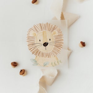 Op de afbeelding: Een aquarel schilderij van een leeuwenkop met een bruine manen en groene bladeren. Het schilderij is op een witte achtergrond met bruine eikels eromheen.