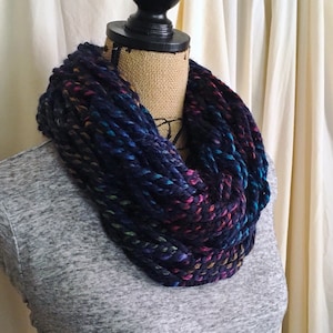 May include: A dark blue infinity scarf with a multi-colored yarn pattern. The scarf is made of a soft, chunky yarn and is perfect for keeping warm in the winter.