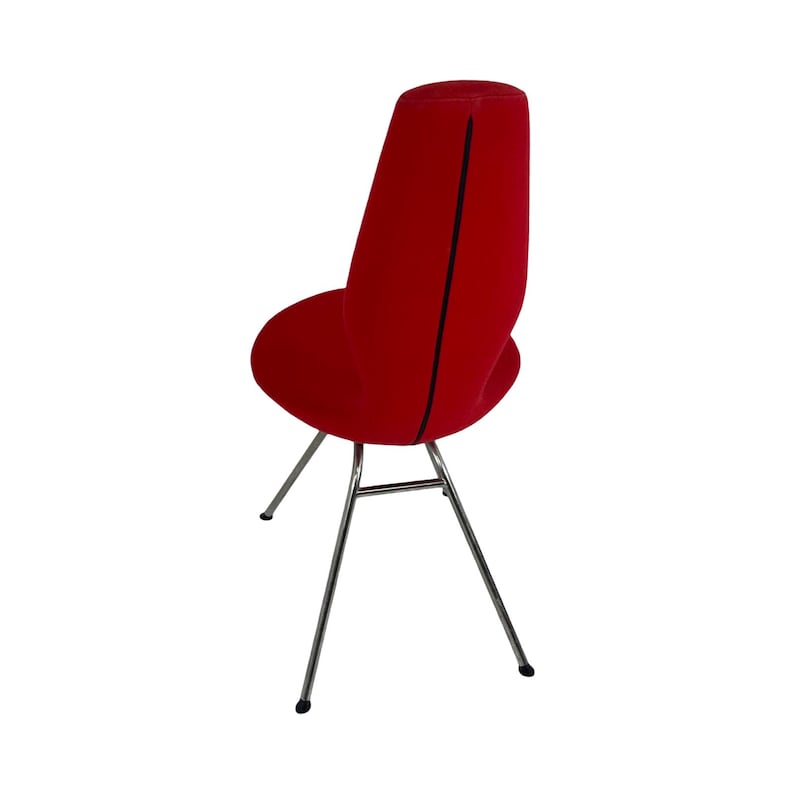 May include: A red velvet chair with a tall, slender back and a chrome base. The chair has a unique, modern design.