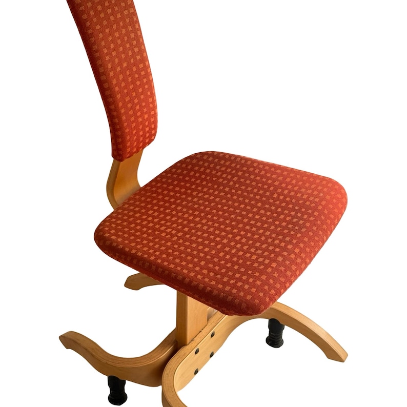 Puede incluir: Silla tapizada naranja con asiento cuadrado y respaldo curvo. La silla tiene una estructura de madera y una tela estampada. La base de la silla tiene un dise&ntilde;o curvo y patas negras.