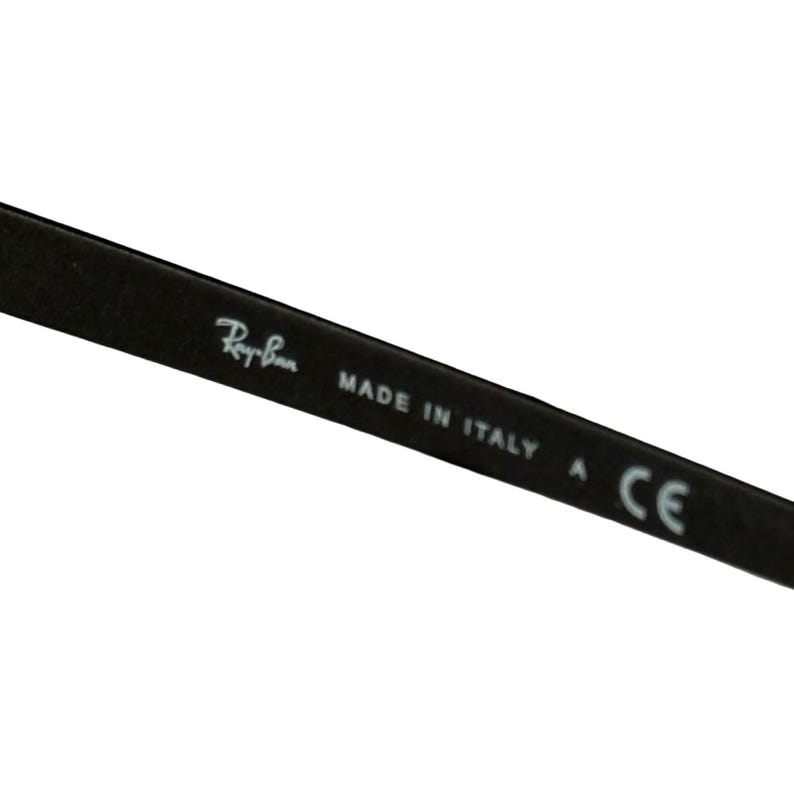 May include: Close-up of a black eyeglass arm with the Ray-Ban logo and the text "MADE IN ITALY" and "A CE". The arm is angled diagonally across the frame.