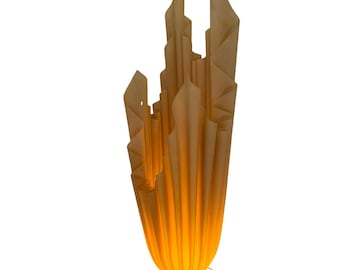 May include: A tall, beige lamp with a unique, abstract design. The lamp features a series of folded, paper-like elements that create a textured, sculptural form. The base is round and the lamp emits a warm, orange glow. The lamp is approximately 30 inches tall.
