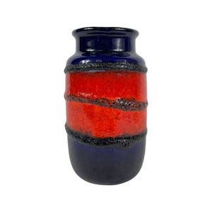 Puede incluir: Un jarrón de cerámica azul y rojo con un esmalte texturizado. El jarrón tiene una forma cilíndrica y una boca ancha.