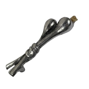 Op de afbeelding: Een zilveren metalen flessenopener in de vorm van twee knoflookbollen met een geknoopte handgreep.