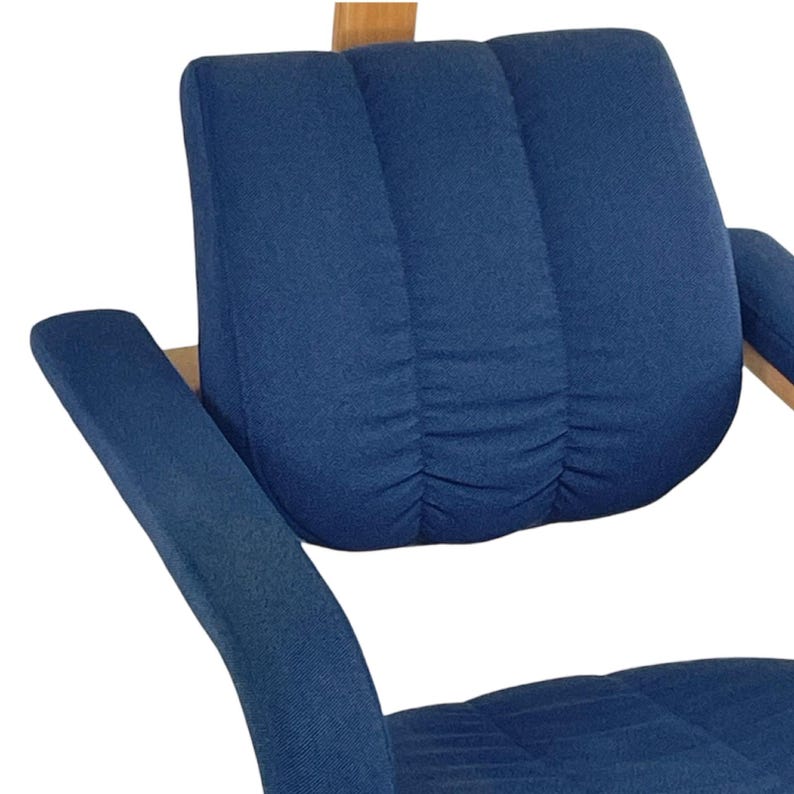 May include: A blue fabric armchair with a high back and curved arms. The chair has a tufted back and a slightly curved seat.