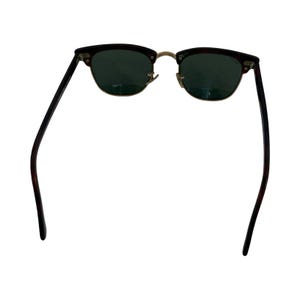 May include: Sunglasses with a dark brown and black patterned frame and green lenses. The sunglasses have a gold-colored bridge and hinges. The arms are dark brown and black.