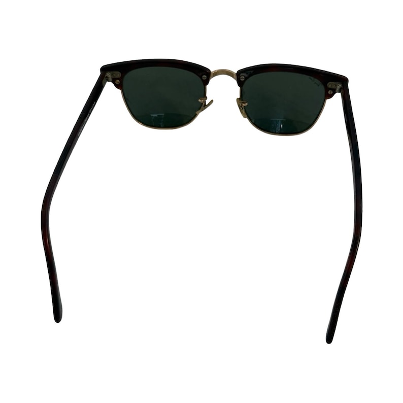 May include: Sunglasses with a dark brown and black patterned frame and green lenses. The sunglasses have a gold-colored bridge and hinges. The arms are dark brown and black.