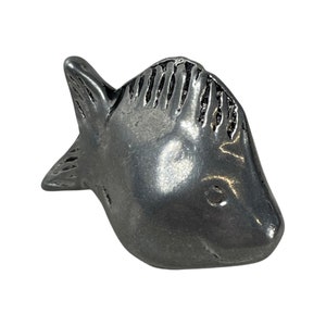 Könnte beinhalten: Eine silberfarbene Fischfigur aus Metall mit einem detaillierten Design. Der Fisch hat einen leicht geöffneten Mund und eine strukturierte Oberfläche.