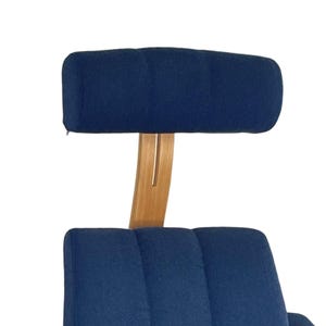 May include: A blue fabric armchair with a wooden frame and a matching headrest. The chair has a tufted back and a curved wooden base.