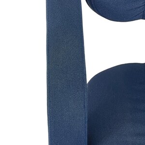 May include: Close-up of a dark blue fabric chair with a textured surface. The chair has a high back and a wide seat.