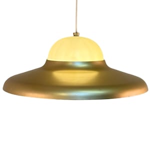 Op de afbeelding: Een retro hanglamp met een messingkleurige, schotelvormige kap en een crèmekleurige, gewelfde bovenkant. De lamp hangt aan een wit snoer. Ideaal om een vleugje vintage toe te voegen aan elke kamer.