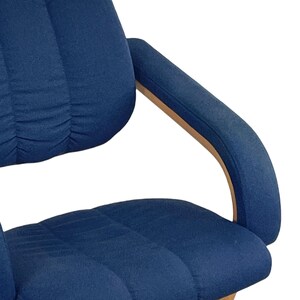 May include: A blue upholstered office chair with a curved wooden armrest. The chair has a padded seat and back.