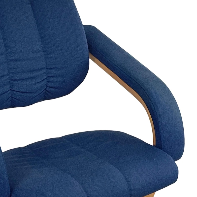May include: A blue upholstered office chair with a curved wooden armrest. The chair has a padded seat and back.