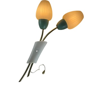 Op de afbeelding: Een vintage wandlamp met twee armaturen. De lamp heeft een gouden metalen frame en twee witte geribbelde glazen lampenkappen. De lampenkappen zijn bevestigd aan tealblauwe bases. De lamp is gemonteerd op een witte wandplaat.