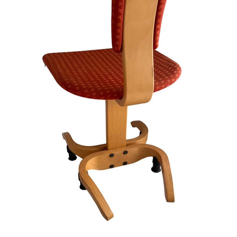 Puede incluir: Silla de oficina vintage con estructura de madera curvada y asiento y respaldo estampados en rojo. La silla tiene una base giratoria y cuatro patas negras. La madera tiene un acabado claro y natural.