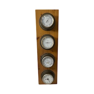 May include: A wooden wall mounted weather station with four analog gauges. The gauges are in a brass finish with white faces and black hands. The gauges measure temperature, humidity, barometric pressure, and time.