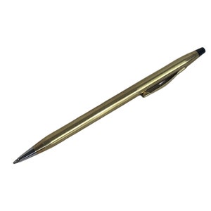 Op de afbeelding: Een gouden balpen met een zwarte inktpatroon en een zilveren punt.