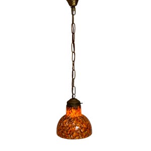 Op de afbeelding: Een hanglamp met een bronzen ketting en een gespikkelde, oranje en bruine glazen kap. De lamp heeft een klassiek ontwerp, geschikt voor binnenverlichting.