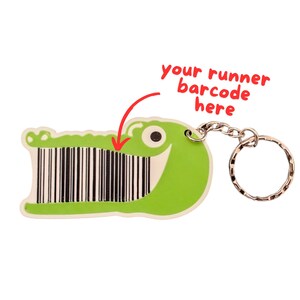 May include: A green alligator-shaped keyring with a barcode design for a runner's barcode. The keyring has a silver chain and ring. Red text says "your runner barcode here".