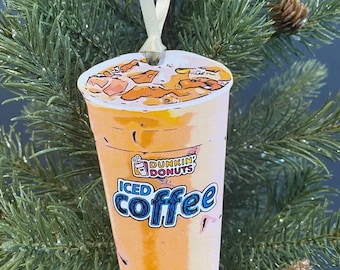 Op de afbeelding: Een Dunkin' Donuts-ornament in de vorm van een ijskoffie, met een cartoonillustratie van een beker ijskoffie met de tekst "ICED coffee" en het Dunkin' Donuts-logo.