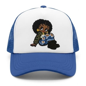 May include: A blue and white trucker hat featuring an embroidered cartoon character. The character has dark skin, a black afro, and is wearing a green jacket, blue jeans, and black boots. The hat has a blue brim and a white front panel.