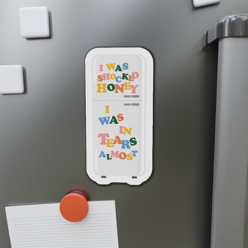 K&ouml;nnte beinhalten: Ein wei&szlig;er K&uuml;hlschrankmagnet mit dem Text "I was shocked honey I was in tears almost" in bunten Buchstaben.