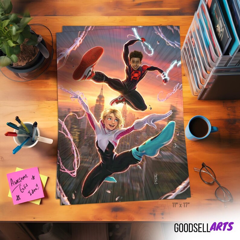 Op de afbeelding: Een kleurrijke poster met twee stripfiguren in actieposities tegen een stadsachtergrond. De poster is 28 x 43 cm groot en bevat de tekst "GOODSELLARTS". Een kopje koffie, een bril en pennen liggen op het houten oppervlak.
