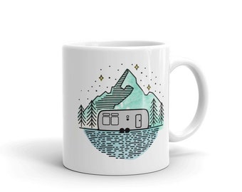 May include: White ceramic mug with a graphic design of a camper parked in front of a mountain lake with stars in the sky. The design is in a minimalist style with a blue and green color scheme.