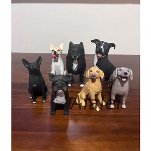 Puede incluir: Siete figuritas de perros personalizadas, cada una con una raza y una pose diferentes. Las figuritas están pintadas en colores realistas y tienen detalles precisos. Las figuritas están dispuestas sobre una superficie de madera.