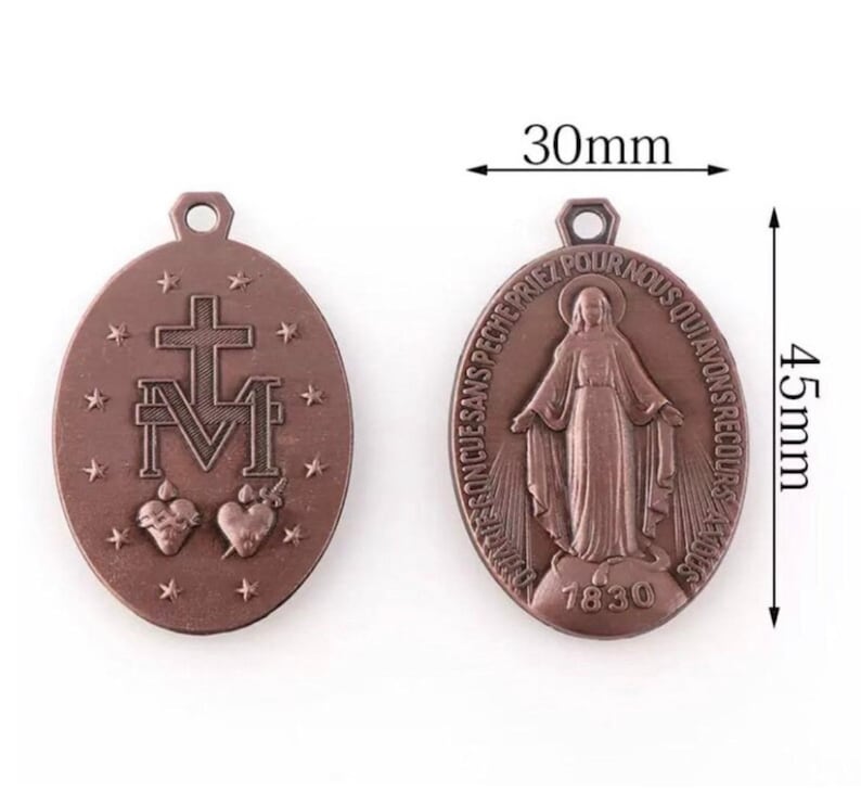 May include: Two bronze-colored oval pendants. One pendant features a cross above the letter "M" with two hearts and stars. The other pendant shows a figure with text and the year 1830. Each pendant is 1.77 inches long and 1.18 inches wide.