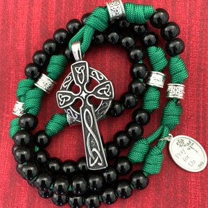 May include: Black and green rosary beads with a silver Celtic cross pendant and a silver charm that says "Pray for Us".