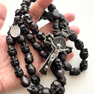 May include: Black skull bead rosary with a silver St. Benedict medal and a silver crucifix with the inscription "INRI".