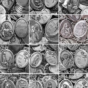 May include: A collection of silver oval-shaped religious medallions with various images and text, including "Pray for Us" and "Have Mercy on Us".